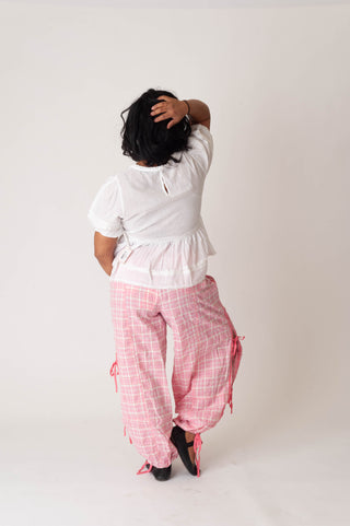 Person wearing a white top and pink checkered pants on a plain background
