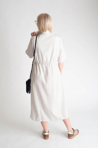 women wearing a button up dress on a white background.