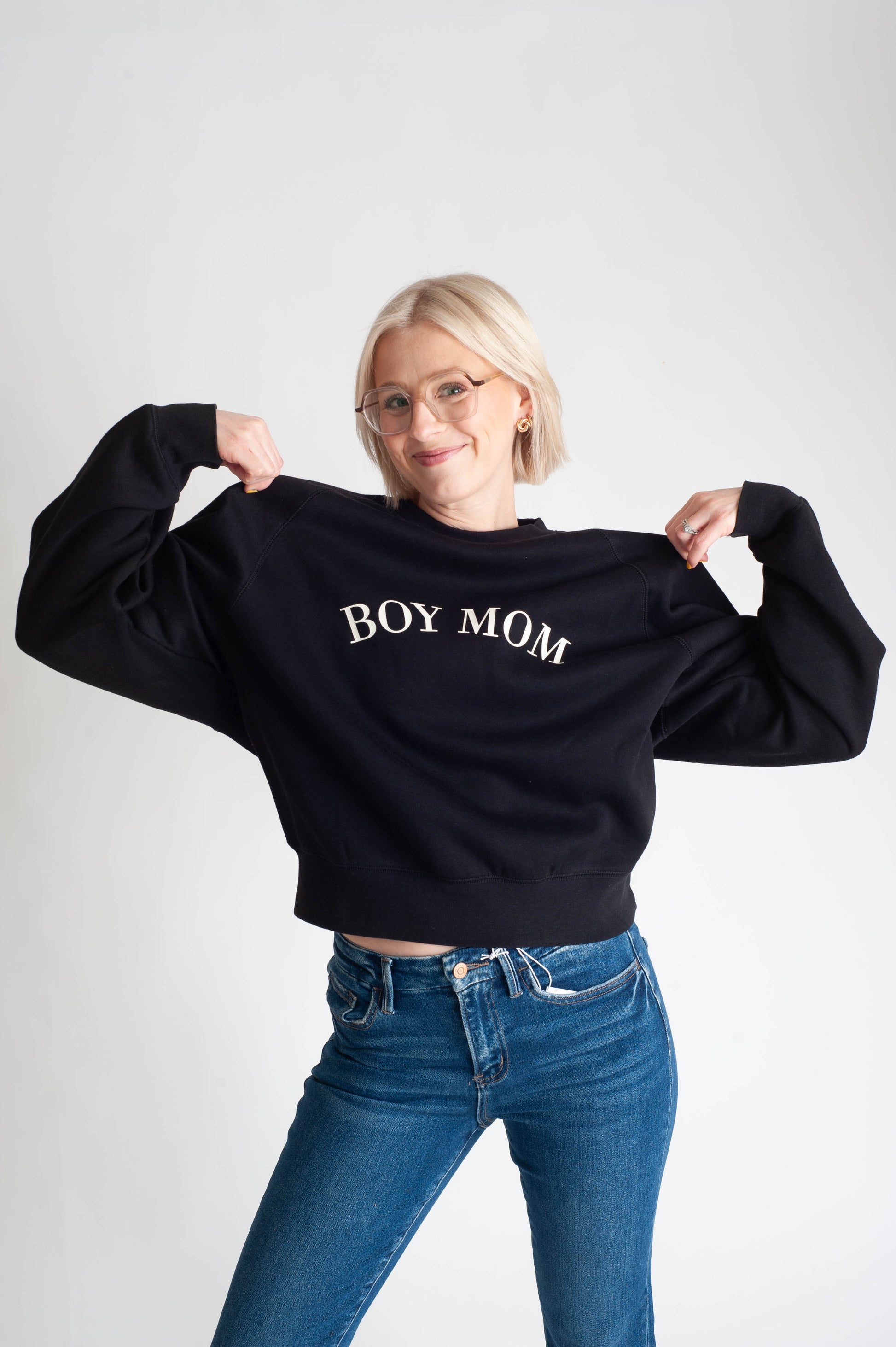 Person wearing a black sweatshirt with 'BOY MOM' text on a white background