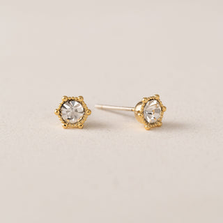 A person wearing gold-plated brass crystal stud earrings.