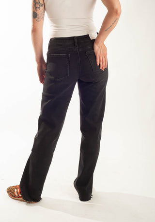 A person shown from the back wearing black straight-leg jeans, a white ribbed tank top, and brown sandals against a plain white studio background.