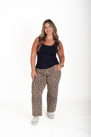 Woman wearing a black top and leopard print pants on a white background