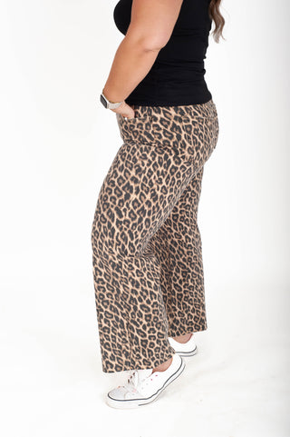 Person wearing leopard print pants on a white background
