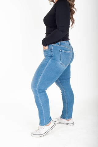 Person wearing blue jeans and a black top on a white background