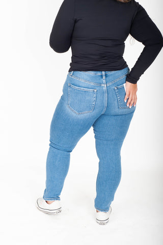 Person wearing blue jeans and a black top on a white background