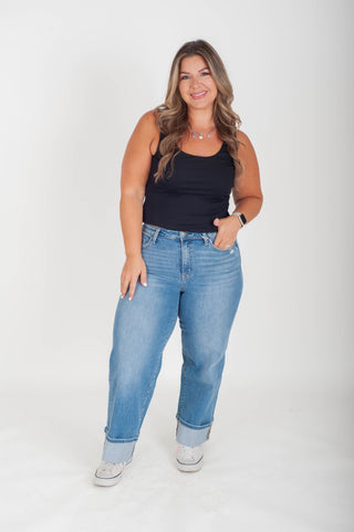 Woman wearing a black tank top and blue jeans on a white background