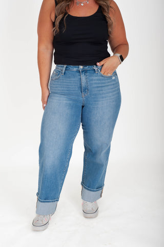 Person wearing blue jeans and a black top on a white background