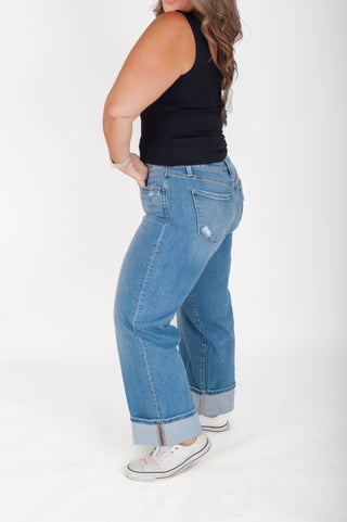Person wearing blue jeans and a black top on a white background