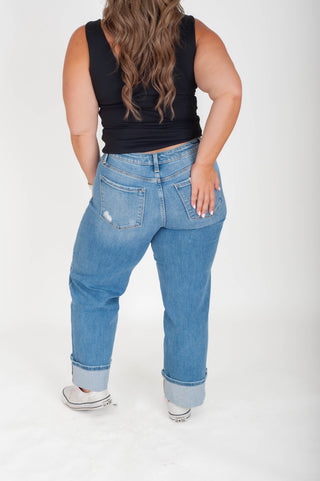 Person wearing blue jeans and a black top on a white background