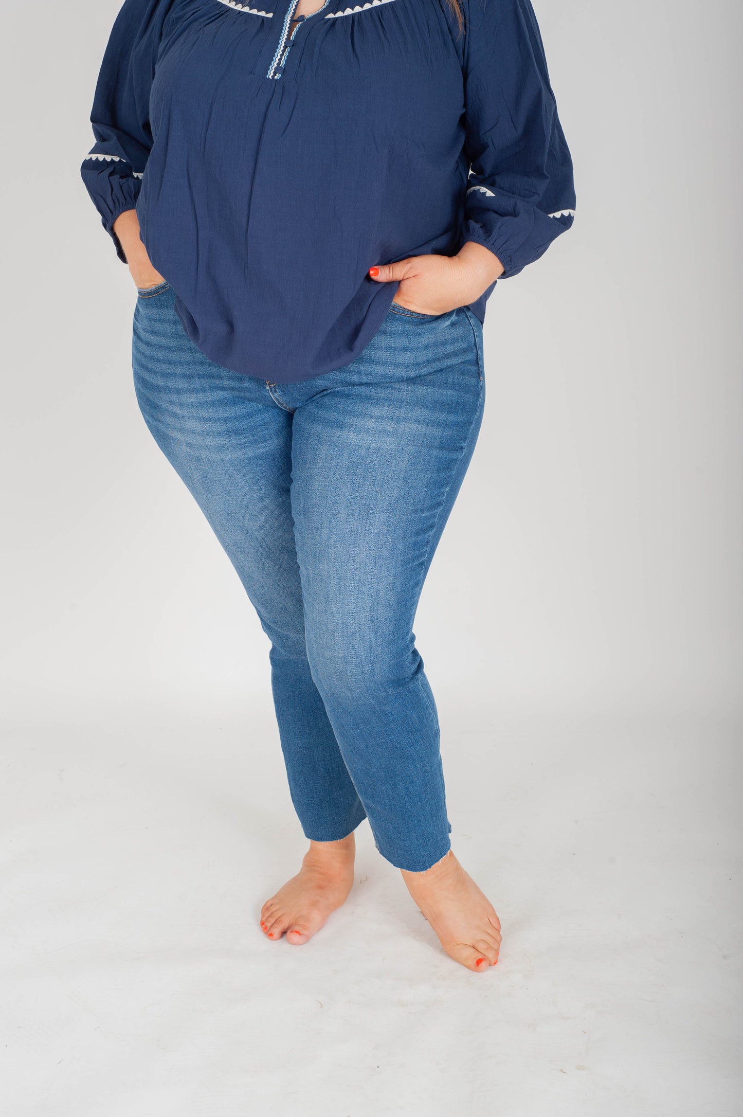 Person wearing a navy blue top and blue jeans on a white background