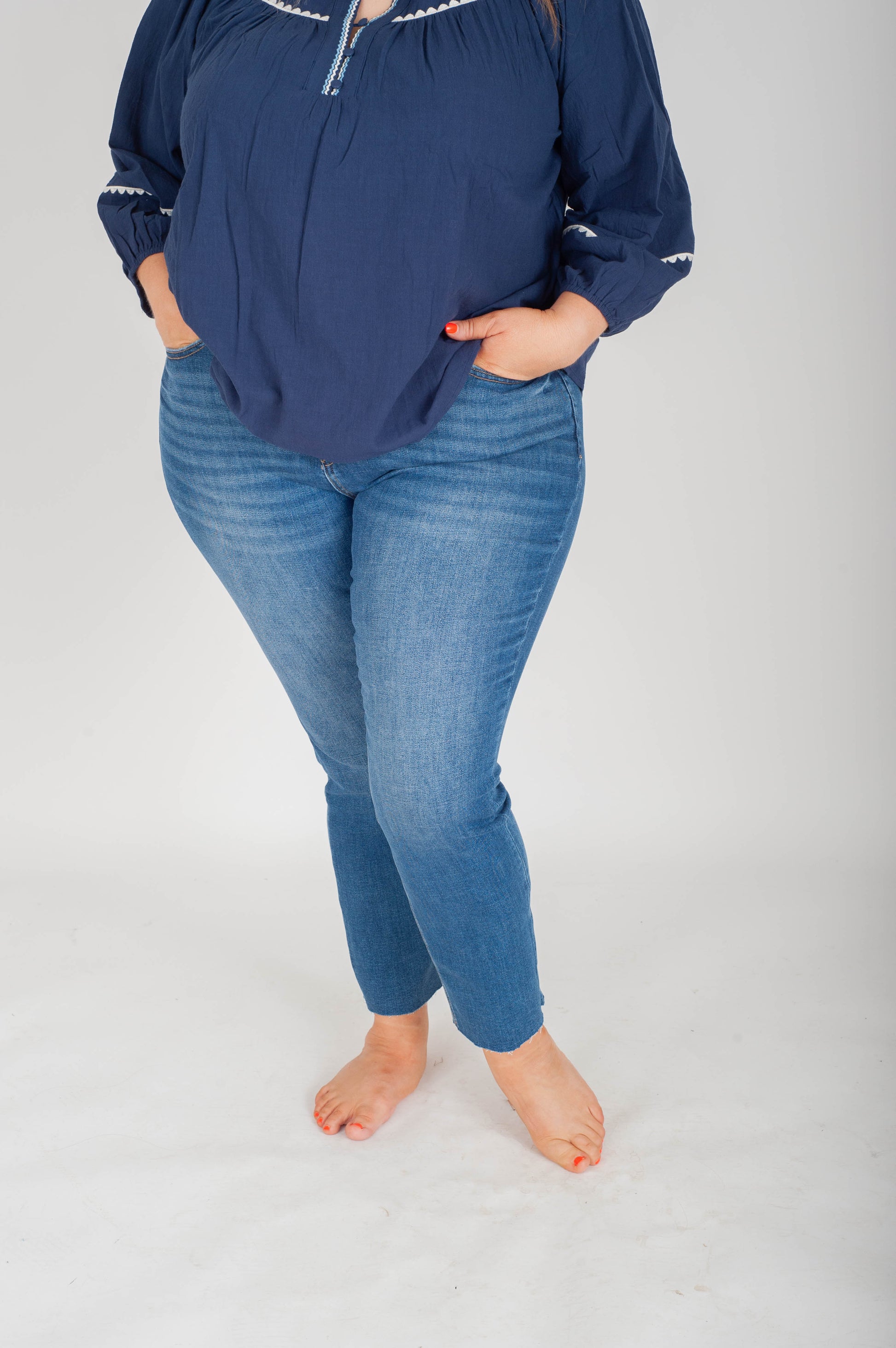 Person wearing a navy blue top and blue jeans on a white background