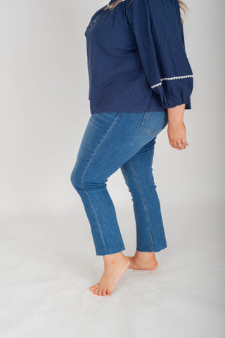 Person wearing a navy blue top and blue jeans on a white background