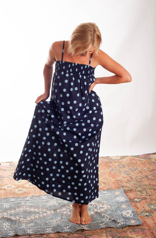 Women wearing a blue polka dot dress against a neutral background.