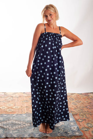 Women wearing a blue polka dot dress against a neutral background.