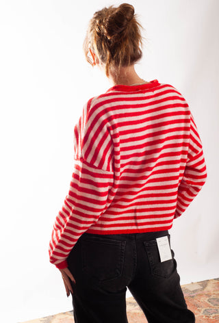 A Women wearing a striped pink and red cardigan against a white background. 