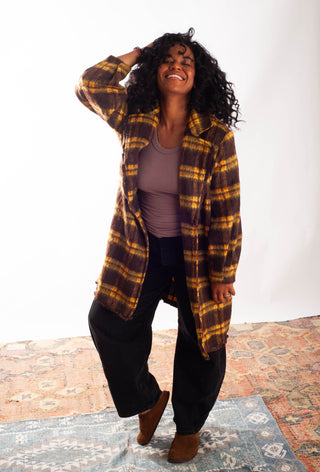 Women wearing a yellow plaid coat against a white background. 