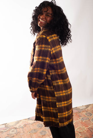 Women wearing a yellow plaid coat against a white background. 
