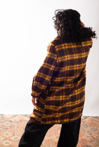 Women wearing a yellow plaid coat against a white background. 