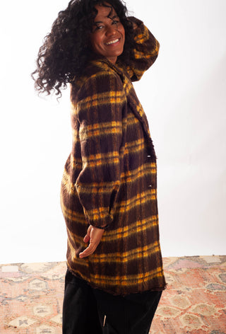 Women wearing a yellow plaid coat against a white background. 