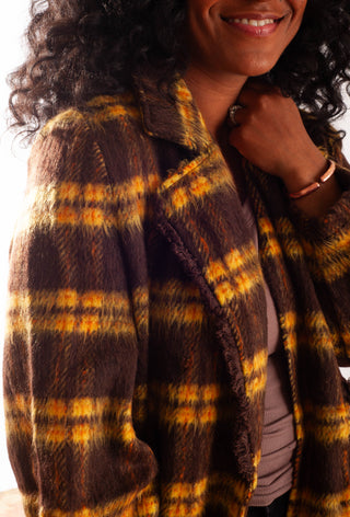 Women wearing a yellow plaid coat against a white background. 