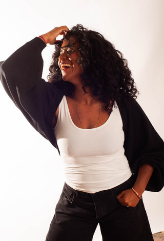 A women wearing a black shrug cardigan against a white neutral background. 