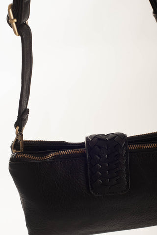 Close-up of a black leather shoulder bag with a woven strap detail and gold-tone zipper hardware, shown against a plain light background.