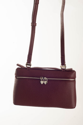 A burgundy pebbled leather handbag with a top zipper, silver-tone double-lock hardware, and a matching shoulder strap, shown against a plain white background.
