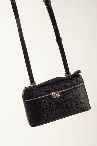 A black pebbled leather crossbody bag with a silver-tone front zipper and a decorative silver clasp, suspended against a plain white background.