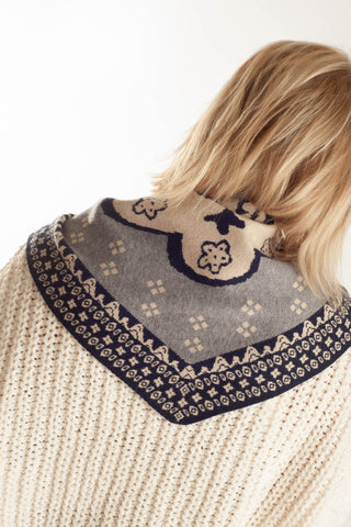 A close-up back view of a person wearing a cream knit sweater with a large gray and navy patterned collar.