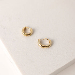 a pair of  gold earrings laying flat on a table