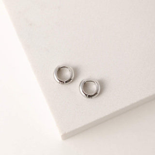a pair of silver earrings laying flat on a table