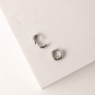 a pair of silver earrings laying flat on a table