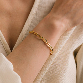 Gold bracelet on a wrist with a neutral background