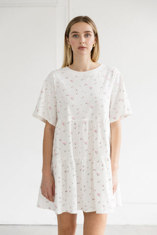 Woman wearing a white dress with a subtle pattern against a plain background