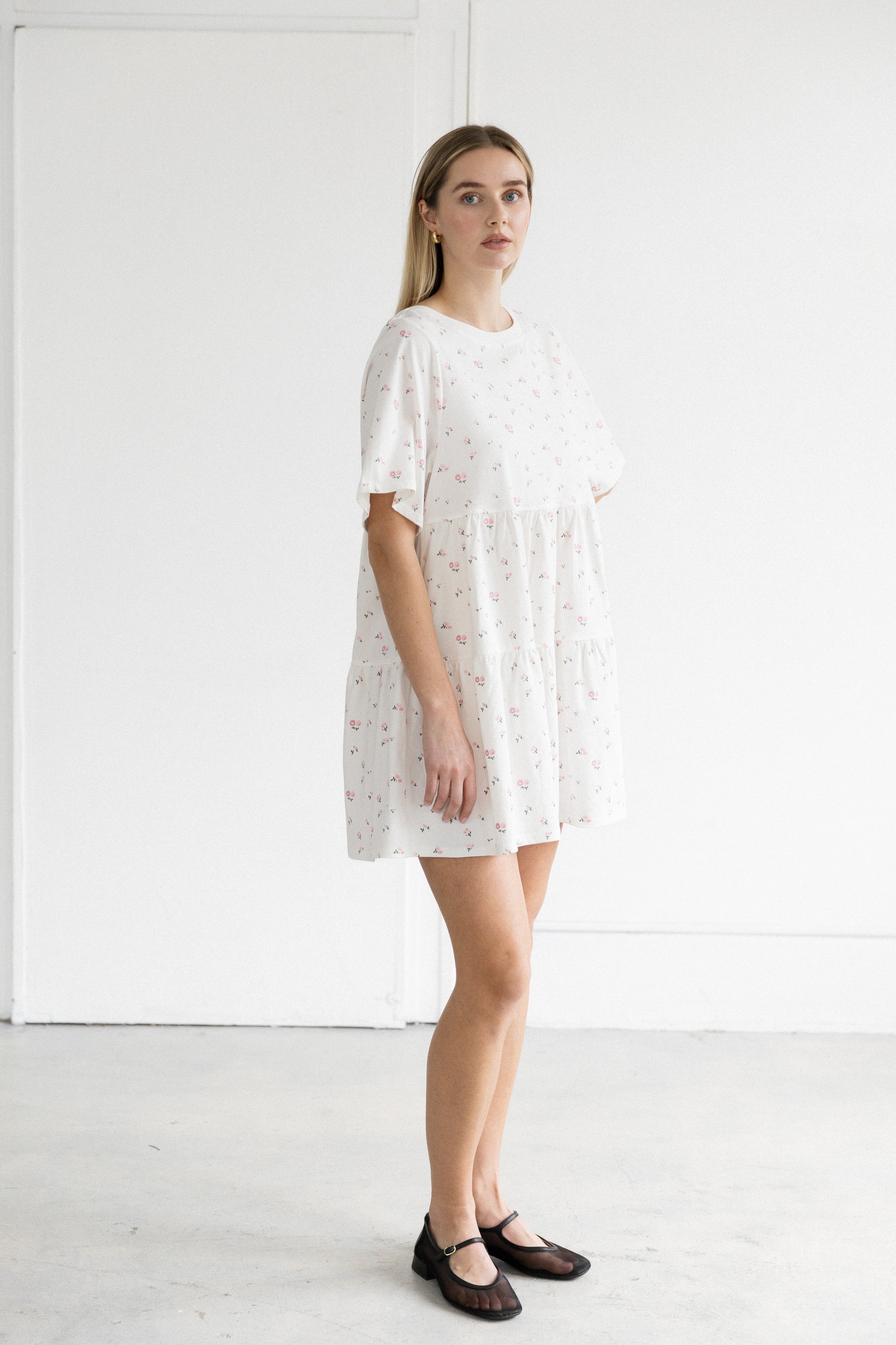 Woman wearing a white dress with a subtle pattern against a plain white background