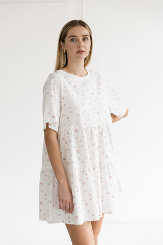 Woman wearing a white dress with a subtle pattern on a plain background
