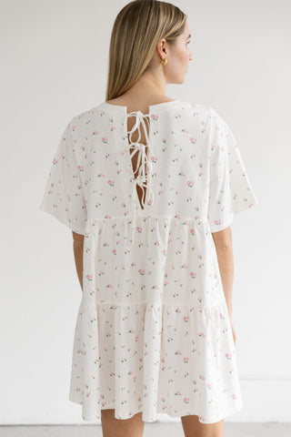 White floral dress with a lace-up back worn by a person on a white background
