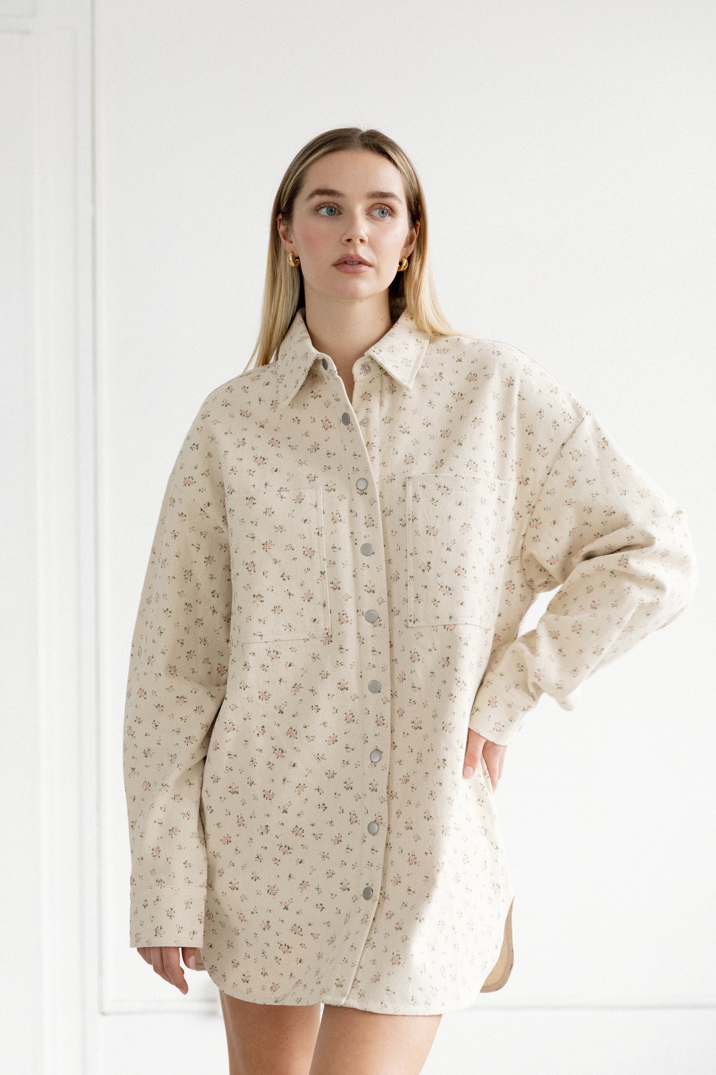 Woman wearing a beige patterned shirt dress against a white background