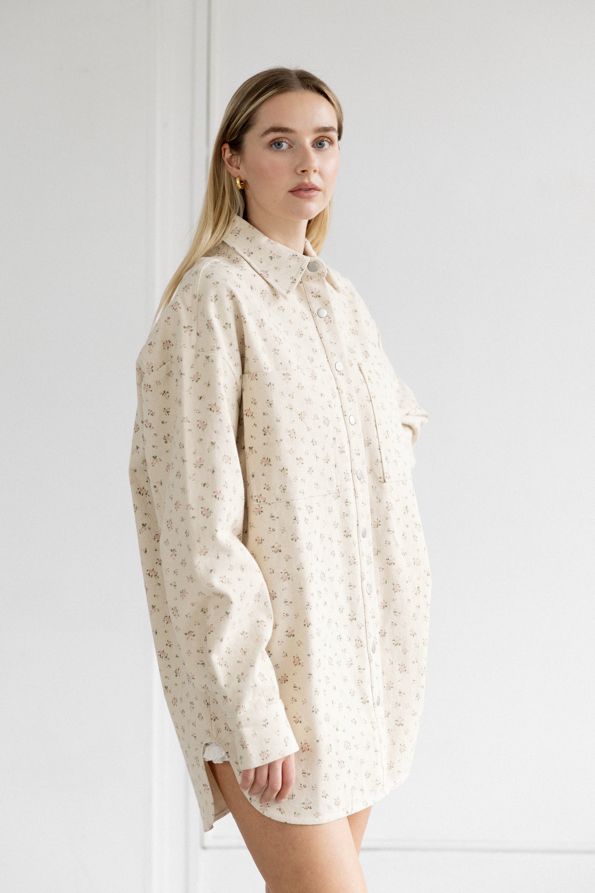 Woman wearing a cream-colored patterned shirt against a white background