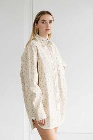 Woman wearing a cream-colored patterned shirt against a white background