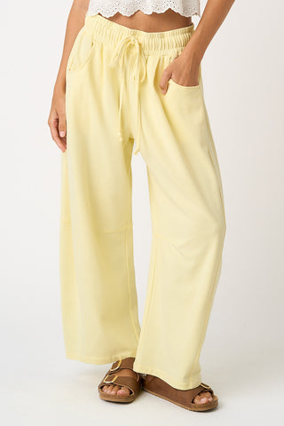 Light yellow wide-leg pants worn by a person on a white background