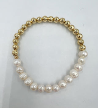 a beaded bracelet with half pearls and half gold beads on a table