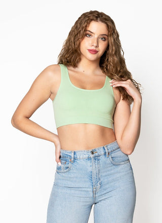 Woman wearing a light green crop top and blue jeans on a white background