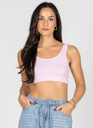 Woman wearing a light purple crop top and blue jeans against a white background