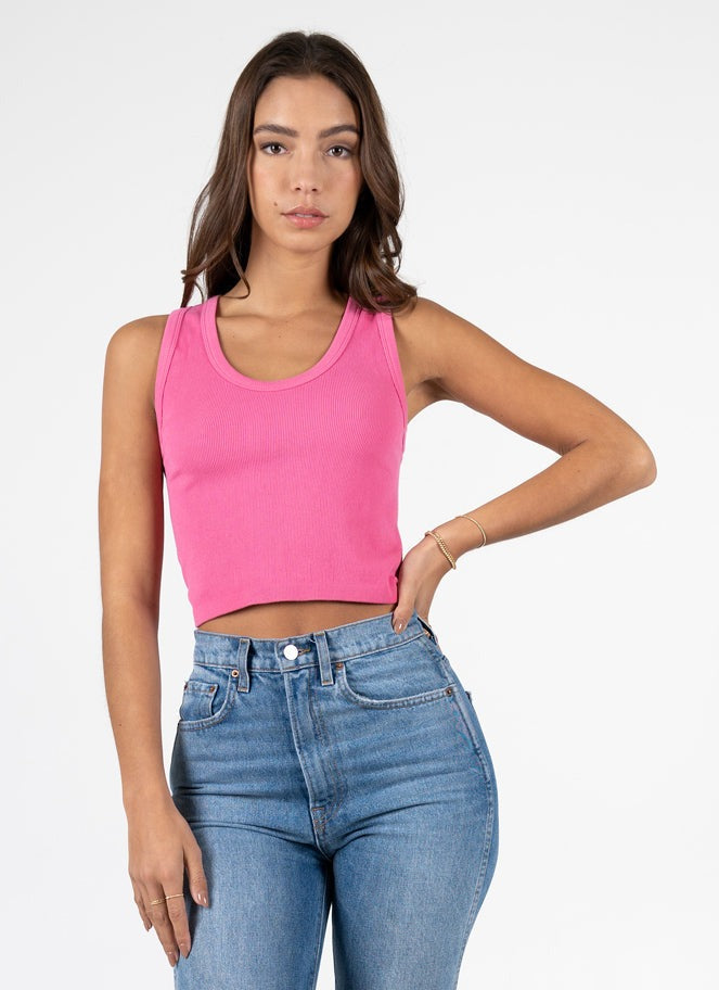 Woman wearing a pink crop top and blue jeans on a white background