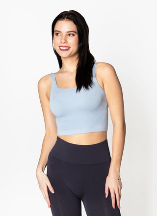 A woman wearing a square neck crop tank in a light blue color, with the tank displaying a ribbed texture.