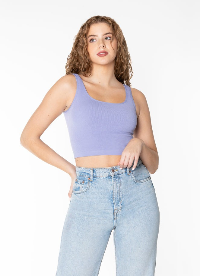 Woman wearing a purple tank top and light blue jeans on a white background