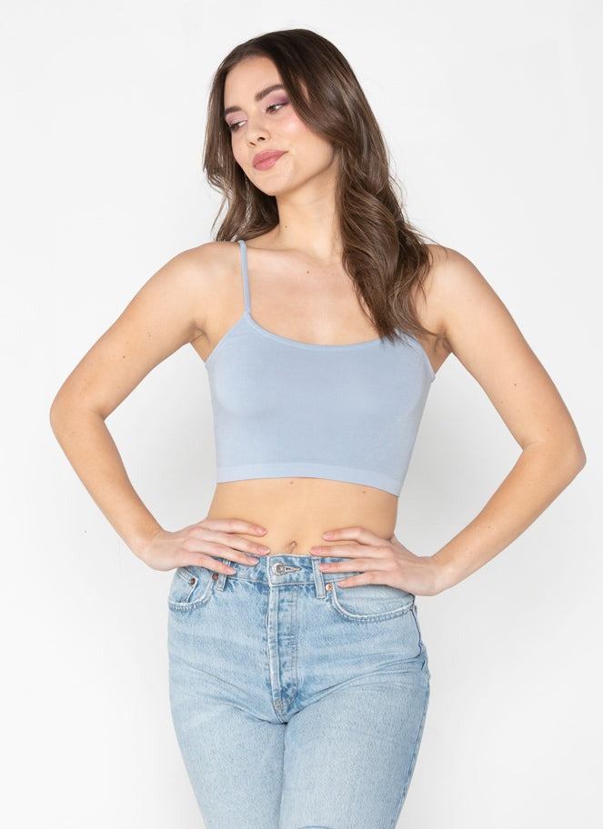 Woman wearing a light blue crop top and jeans on a white background