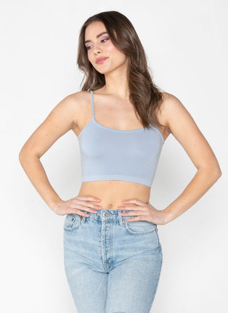 Woman wearing a light blue crop top and jeans on a white background
