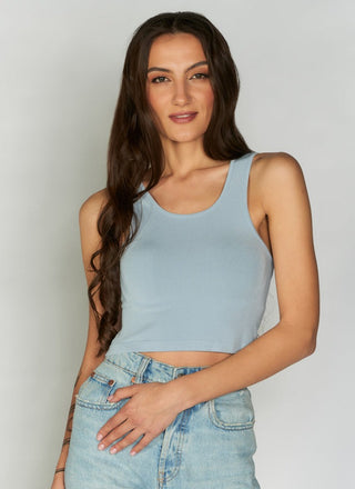 A woman wearing a blue bamboo cropped tank top paired with blue jeans.